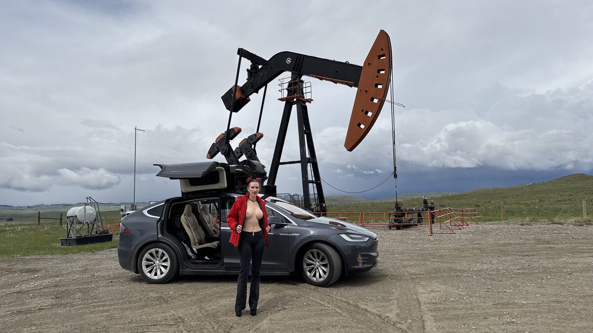 Piper at a pump jack in Alberta, red jacket open